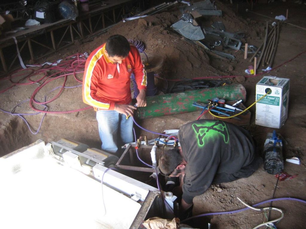 Personas instalando equipos de climatización en proceso de instalación